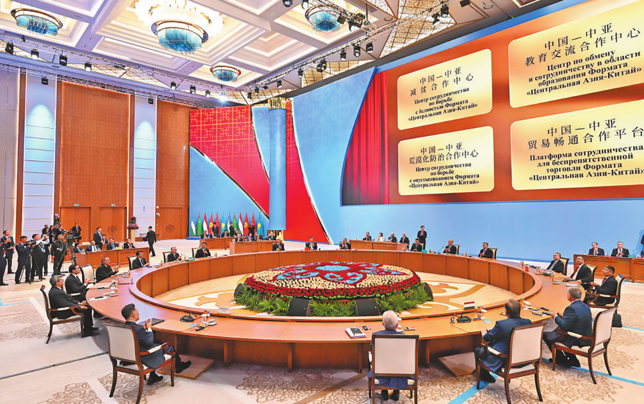འདི་ནི་ཞི་ཅིན་ཕིང་གིས་ཨེ་ཤེ་ཡ་དབུས་མའི་རྒྱལ་ཁབ་ལྔའི་གཙོ་བདག་དང་ལྷན་དུ་ཀྲུང་གོ་དང་ཨེ་ཤེ་ཡ་དབུས་མའི་དབུལ་པོ་ཉུང་གཏོང་གི་མཉམ་ལས་ལྟེ་གནས་དང་། སློབ་གསོ་སྤེལ་རེས་ཀྱི་མཉམ་ལས་ལྟེ་གནས། ཐང་རྒོད་ཅན་འགོག་བཅོས་ཀྱི་མཉམ་ལས་ལྟེ་གནས། ཚོང་དོན་ཤར་བགྲོད་ཀྱི་མཉམ་ལས་ལས་སྟེགས་བཅས་ཀྱི་སྒོ་བྱང་གི་ཡོལ་ཁེབས་འབྱེད་པའི་མཛད་སྒོར་ཞུགས་བཞིན་པ།